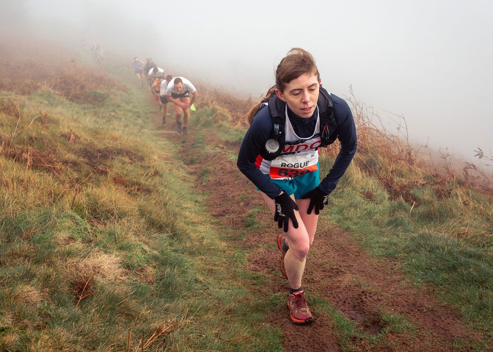 Briony Latter in the Skirrid fell race 2025 coming uphill with hands on knees in the cloud